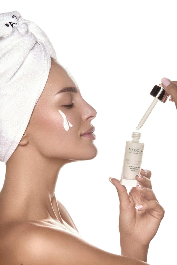"A woman with radiant skin and a towel-wrapped head applying Jurgita Cosmeceuticals Collagen Protect Sun Serum SPF 30 with a dropper, emphasizing its lightweight and nourishing formula.
