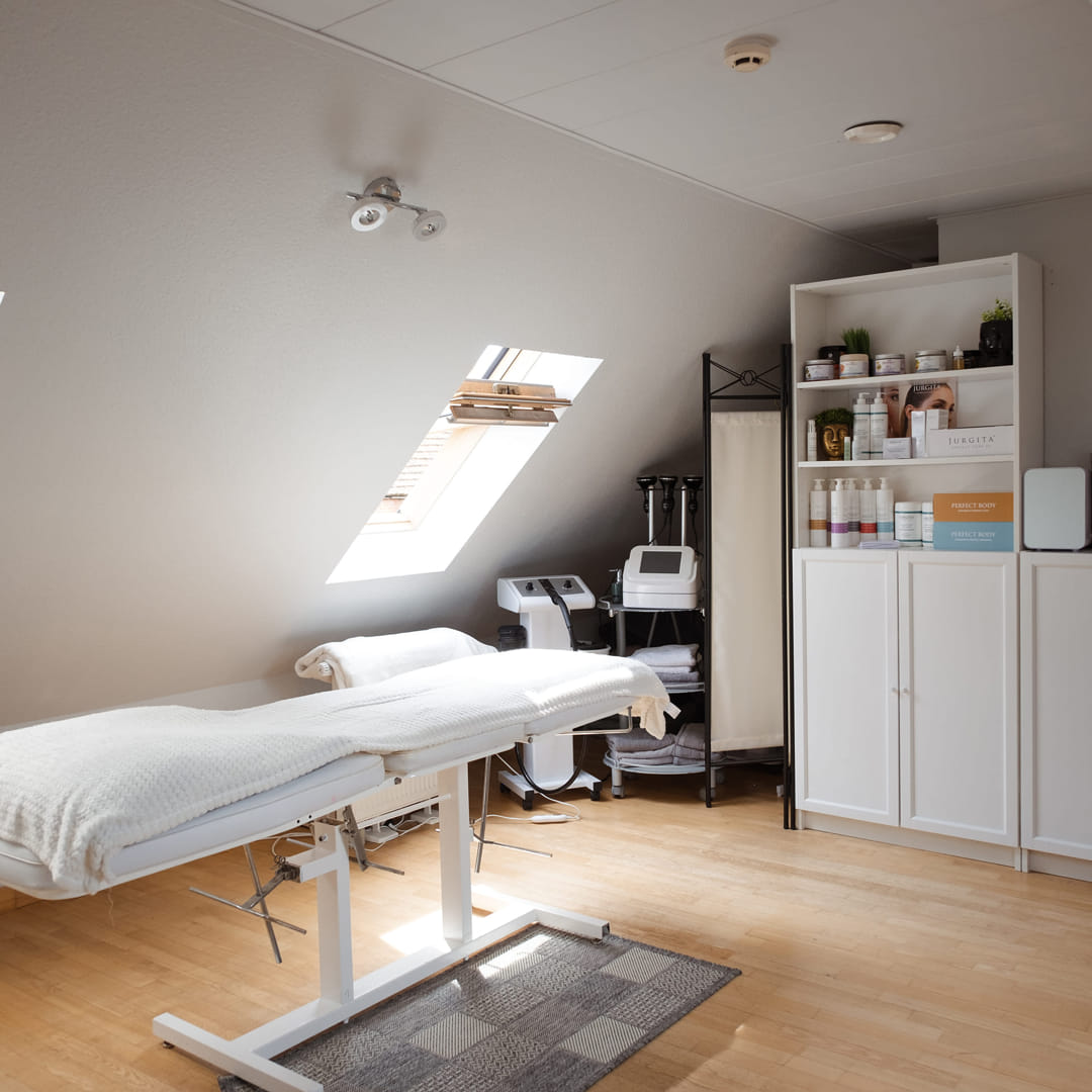 Bright and professional treatment room in Kėdainiai using Jurgita Cosmeceuticals body care products and presotherapy equipment for visible skin refinement results.
