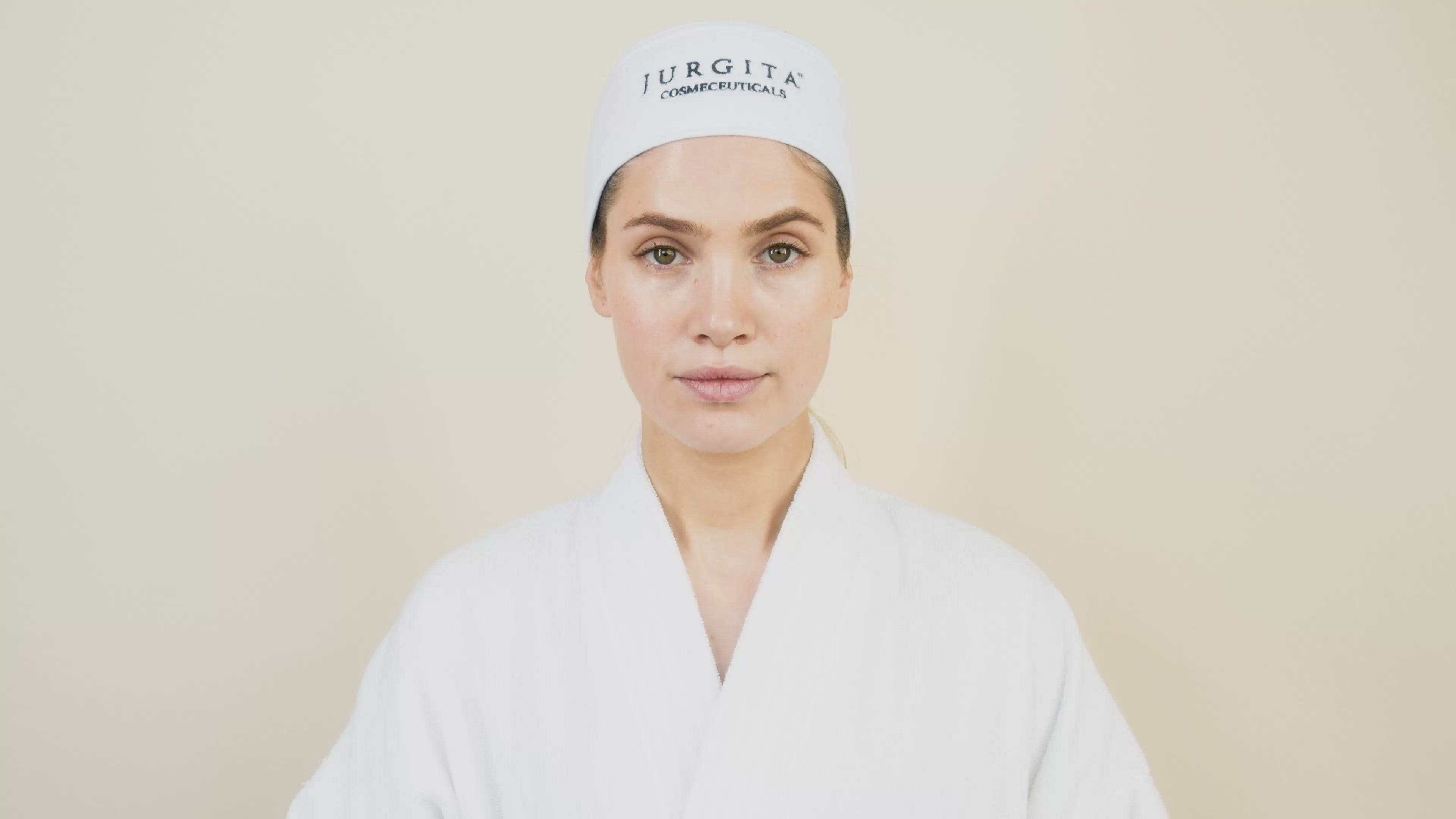 low-motion close-ups of the Jurgita Cosmeceuticals Collagen Tonic bottle as a model gently holds and applies it. The camera captures the luxurious texture and elegant packaging, highlighting its hydrating and balancing benefits.