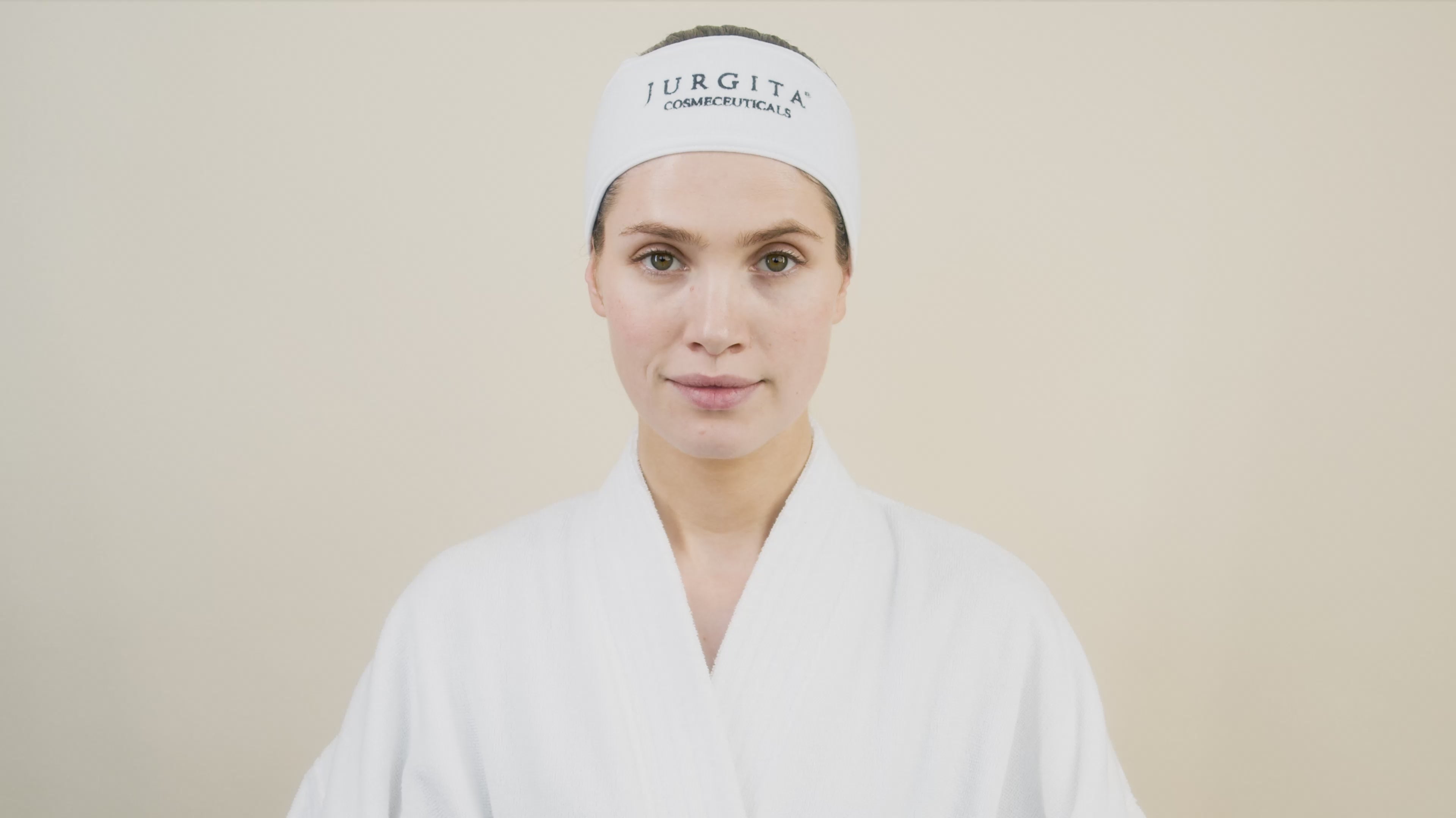 A woman gently applies Jurgita Cosmeceuticals Intensive Tone Up Cream to her face, demonstrating its smooth texture and skin-firming benefits.