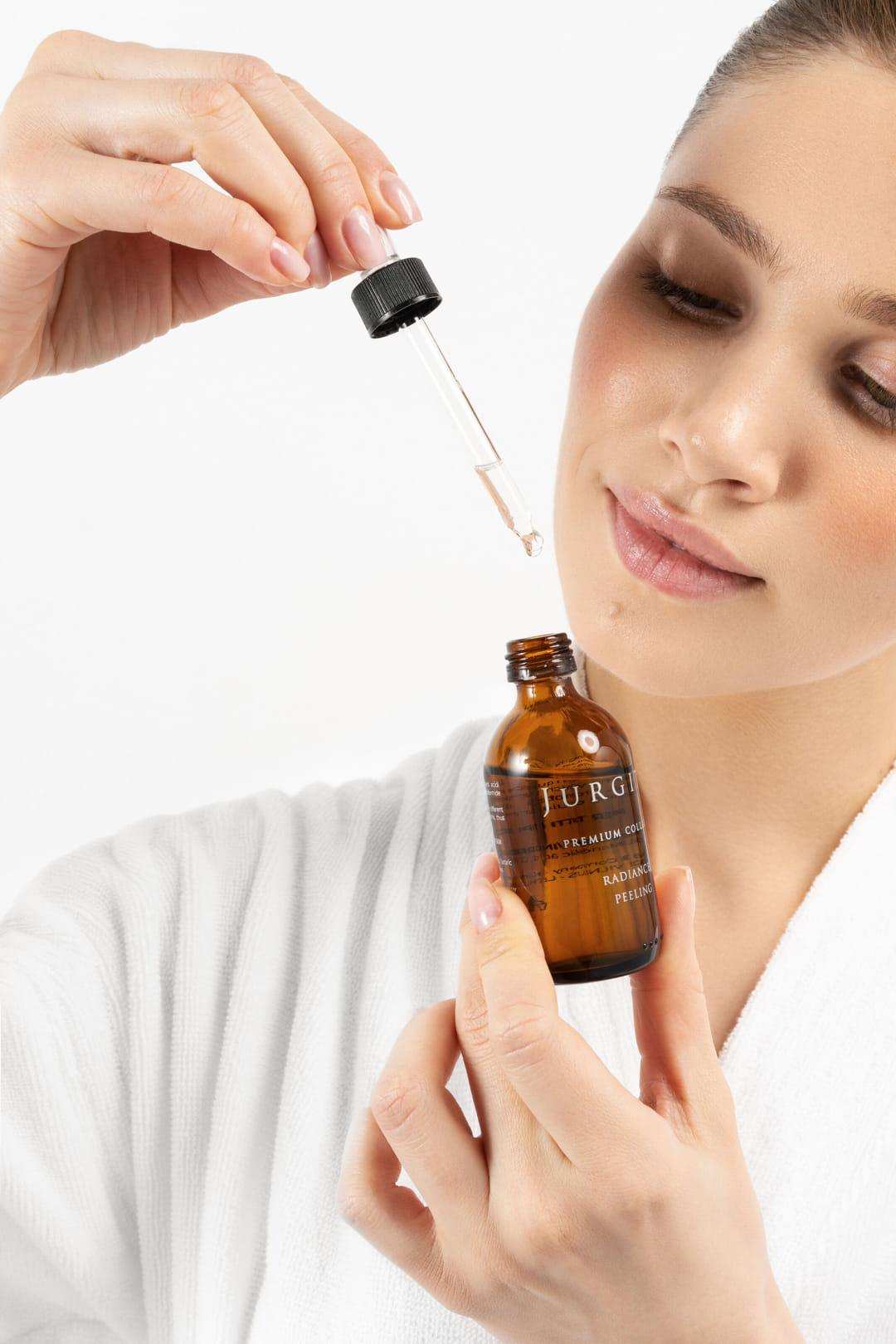 A model carefully dispensing a few drops of the peeling solution from the dropper.