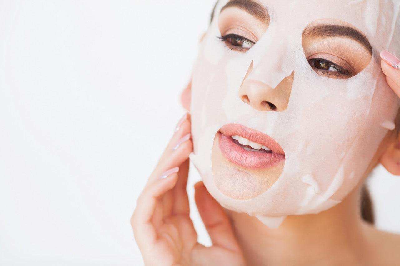 A woman gently adjusting a Jurgita Cosmeceuticals Bio-Cellulose Face Mask, showcasing its ultra-thin, skin-hugging fit for deep hydration and rejuvenation.