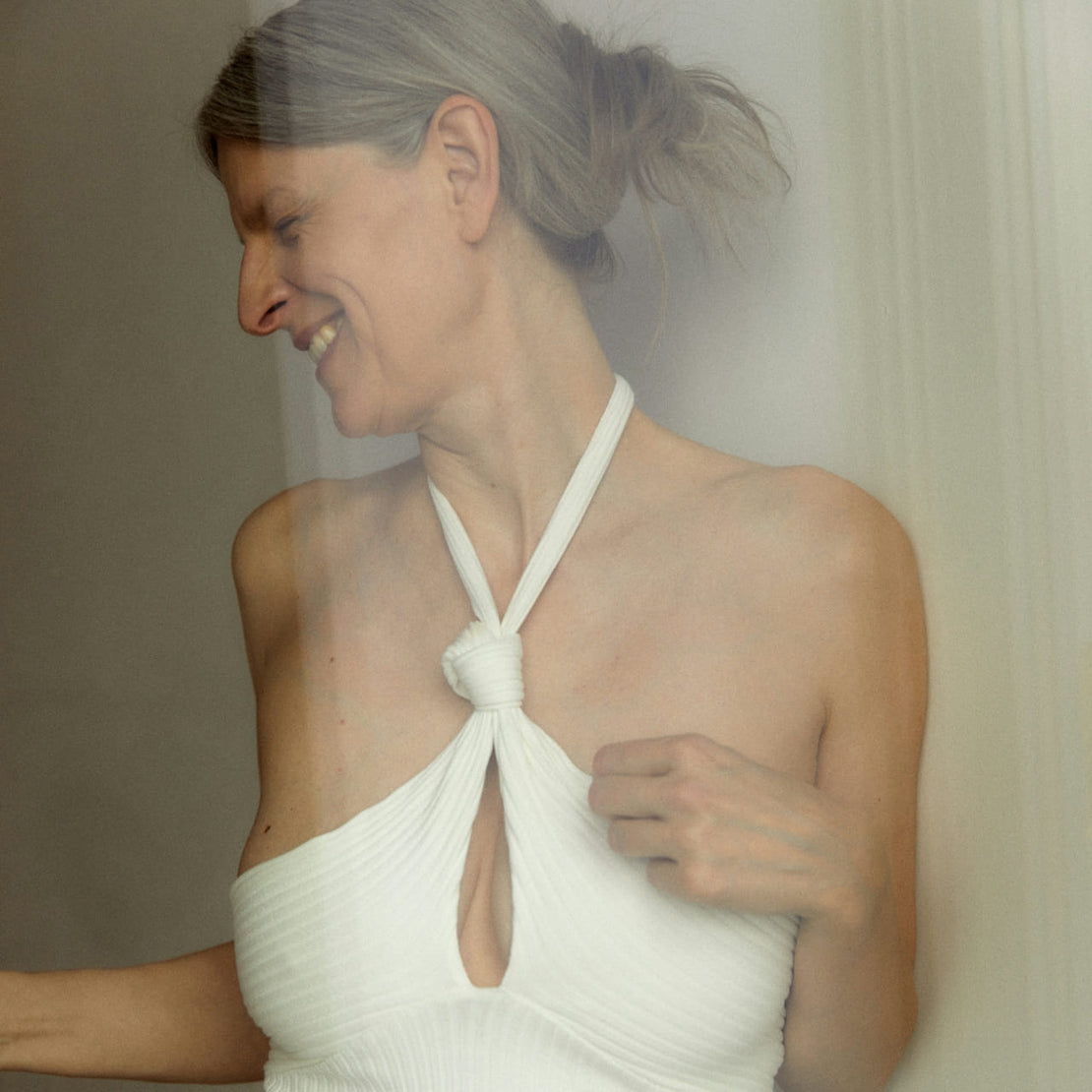 Smiling mature woman in a white dress, radiating confidence and natural beauty — celebrating authenticity and self-love.